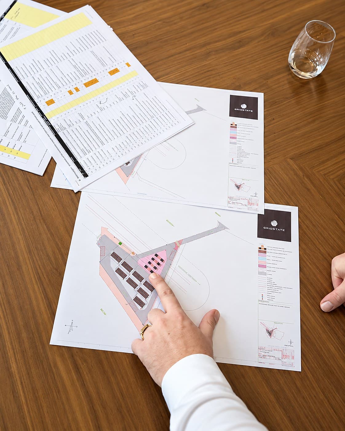 Terreintekeningen en een planning uit een haalbaarheidsstudie, uitgespreid op tafel